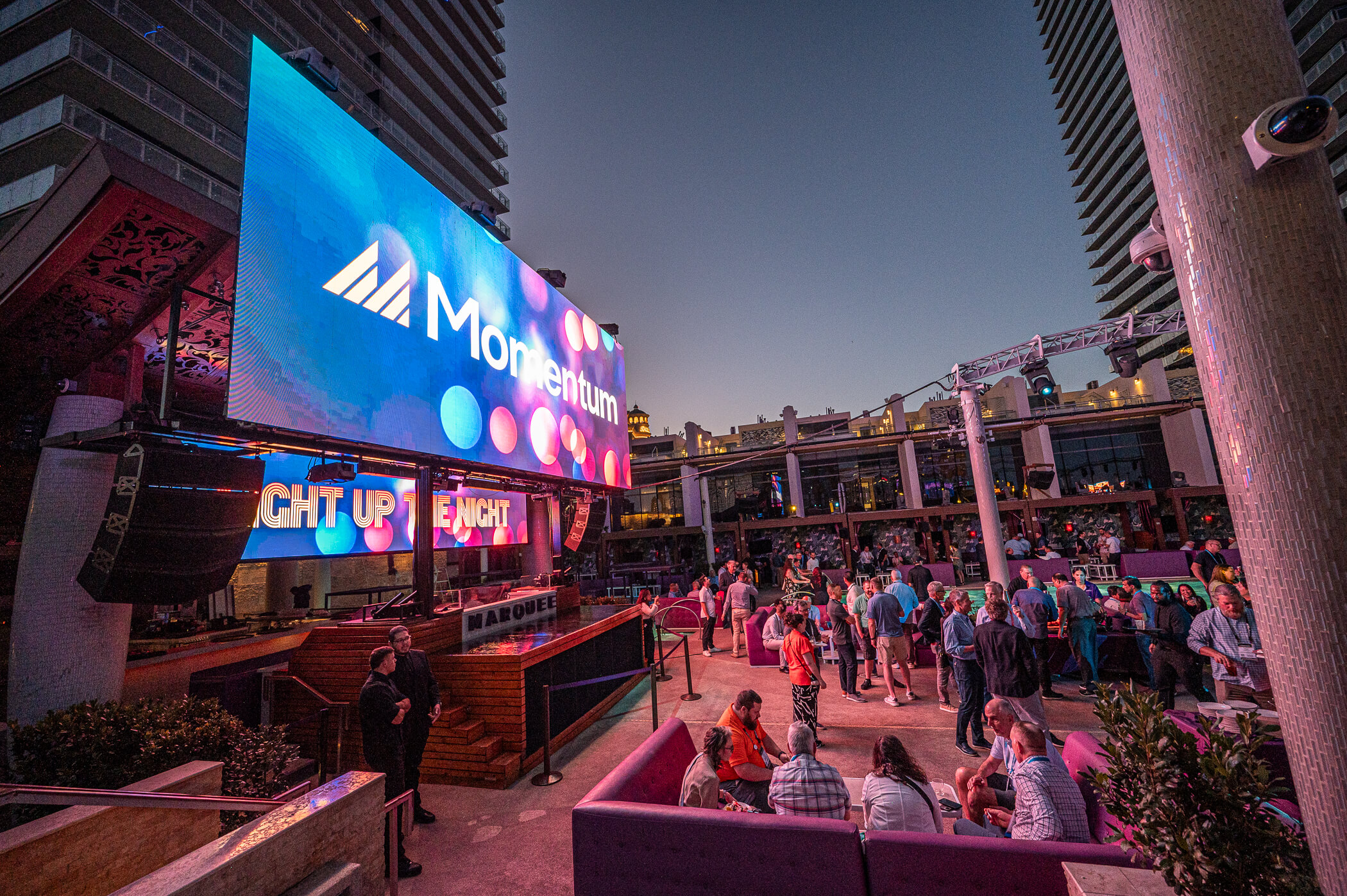 Image of Momentum 2025 large flat tv screen and walkway with attendees.